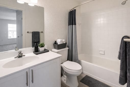 A white bathroom with a toilet, sink, and shower.
