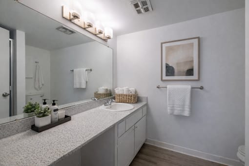 A bathroom with a white counter top and a white sink.