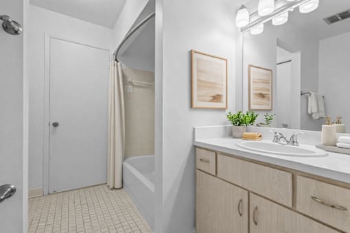 A bathroom with a white sink, a white tub, and a white door.