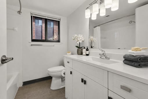 A white bathroom with a toilet, sink, and a window.