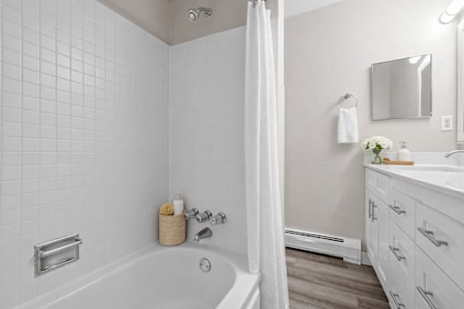 A white bathroom with a tub, sink, and mirror.