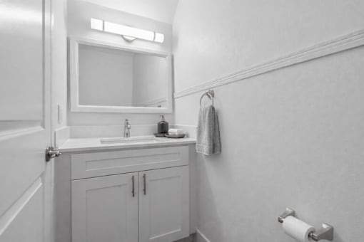 A bathroom with a sink, mirror, and towel rack.
