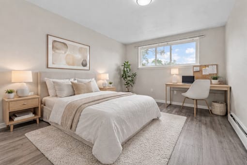 A bedroom with a large bed, a desk with a chair, and a window with a view of the sky.