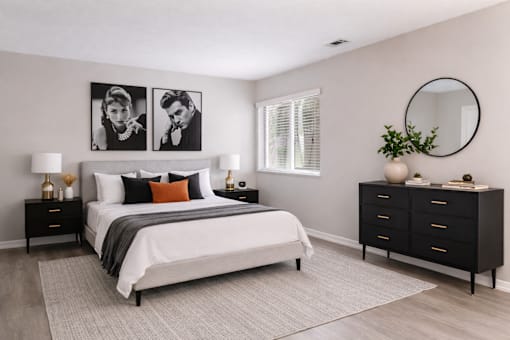 A bedroom with a large bed, a nightstand, and a dresser.