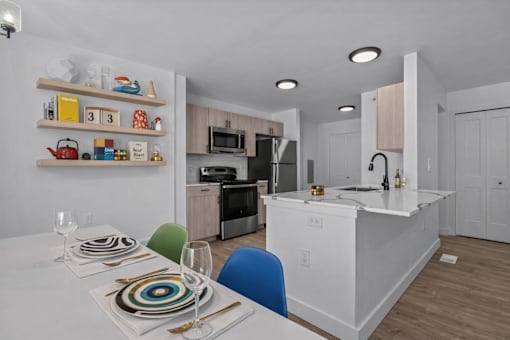 A modern kitchen with a dining table set for two.