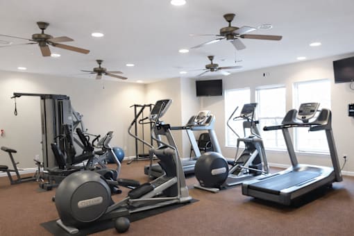A spacious gym with a variety of equipment including treadmills, stationary bikes, and weight machines.