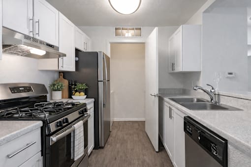 A kitchen with black and white appliances and wooden floors.