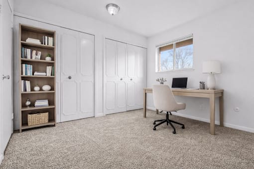 A room with a desk, chair, and bookshelf.