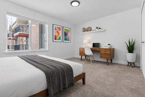 A bedroom with a bed, desk, and chair.