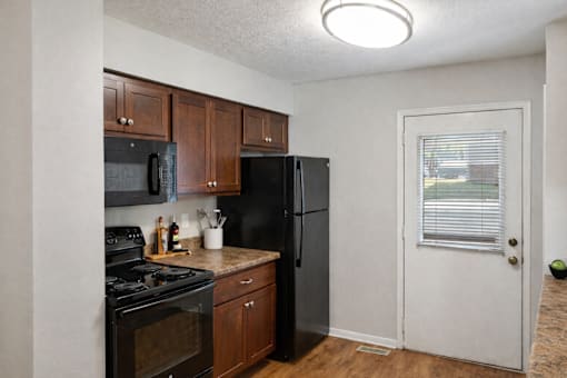 A kitchen with black appliances and wooden cabinets.