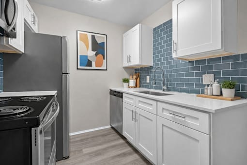 A modern kitchen with a black stove top oven and white cabinets.
