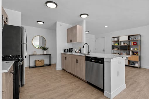 A modern kitchen with wooden floors and stainless steel appliances.
