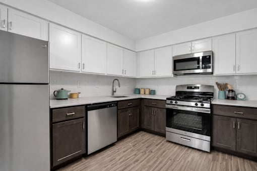 A kitchen with white cabinets and a stainless steel refrigerator. at Rochester Club Apartments, Apartments, Rochester, MI