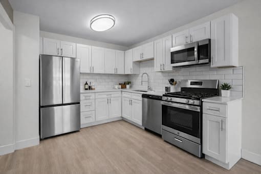 A modern kitchen with stainless steel appliances and white cabinetry.