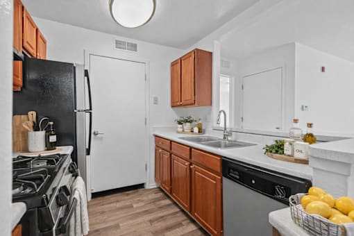 A kitchen with a black refrigerator and wooden cabinets.