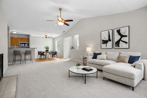 A living room with a white couch, a coffee table, and a ceiling fan.