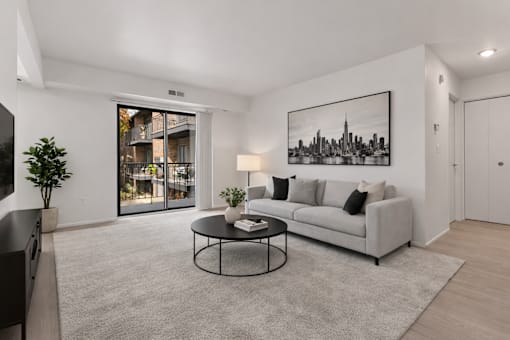 A living room with a grey couch, a coffee table, and a framed picture of a city skyline on the wall.