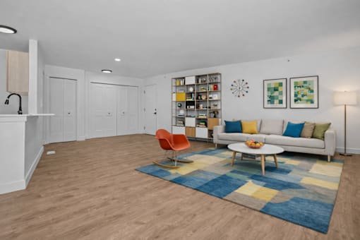 A living room with a white couch, a blue rug, and a white cabinet.