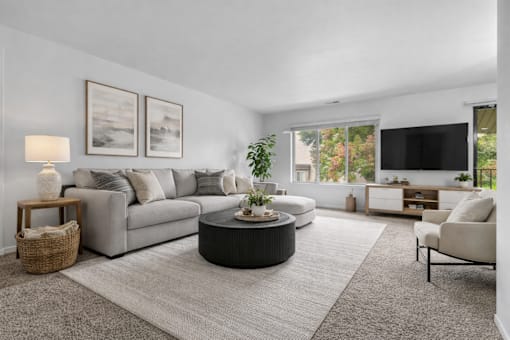 A living room with a grey couch, a round coffee table, and a flat screen TV.