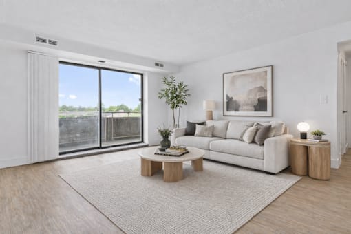 A living room with a white couch, a coffee table, and a large window.
