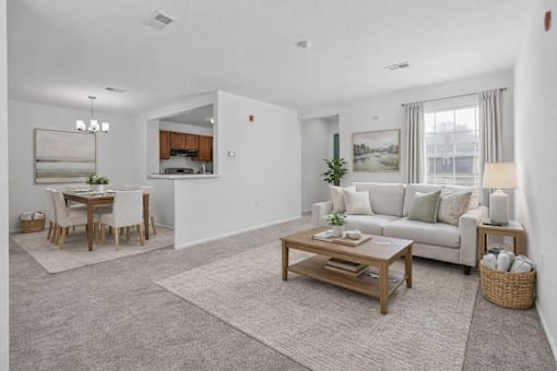A living room with a white couch, a wooden coffee table, and a dining table with chairs.