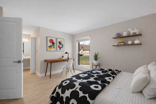 A bedroom with a bed, desk, and chair. at Rochester Club Apartments, Rochester, MI, 48306