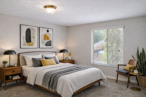 A bedroom with a bed, nightstand, and two framed artworks on the wall.
