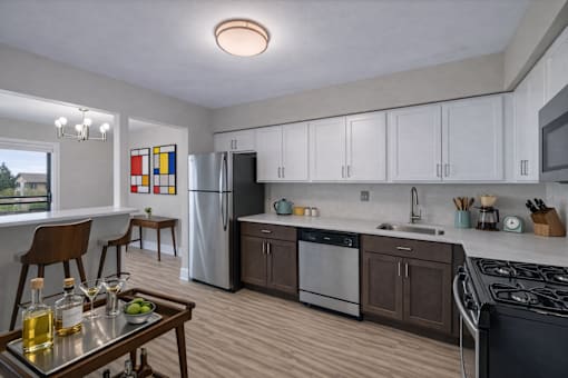 A modern kitchen with a refrigerator, stove, and dining table. at Rochester Club Apartments, Rochester