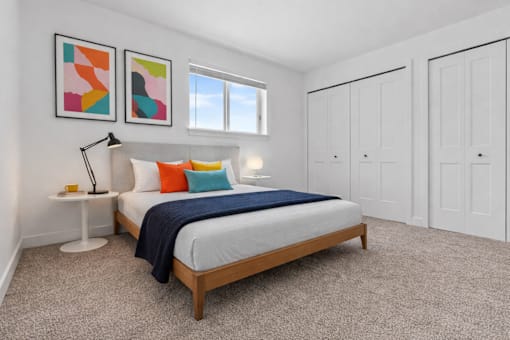 A bedroom with a bed, two lamps, and two framed pictures on the wall.