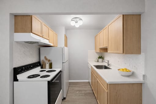 A kitchen with a white stove and wooden cabinets.
