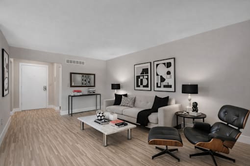 A modern living room with a white couch, a coffee table, and two black chairs. at Rochester Club Apartments, Rochester, MI, 48306