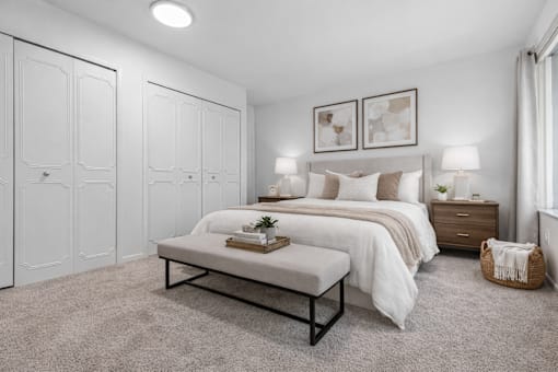 A bedroom with a large bed, a bench, and two nightstands.