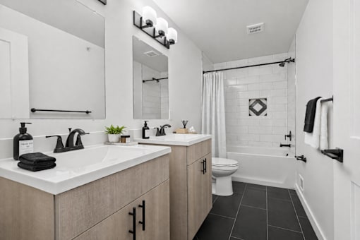 A bathroom with a white sink and black tiles.