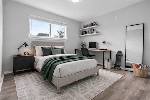 A bedroom with a large bed, a desk with a chair, and a window with a view of trees.