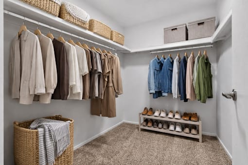 A white closet with clothes and shoes.