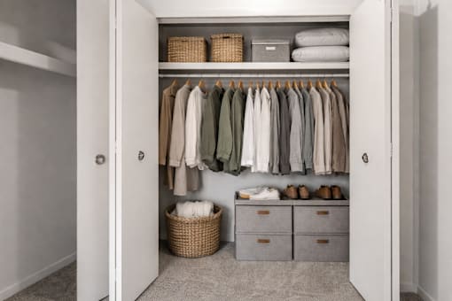 A white closet with clothes and shoes.