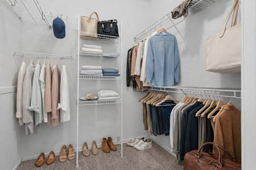 A white closet with clothes and shoes.