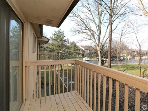 a balcony with a wooden railing and a street in the background