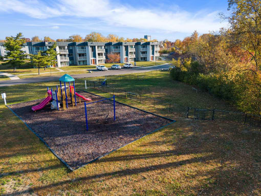 a playground in a park with apartments in the background