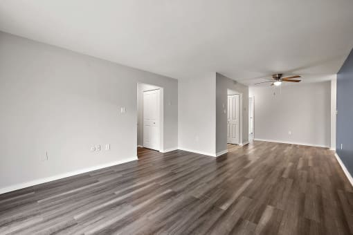 an empty living room with wood flooring and a ceiling fan