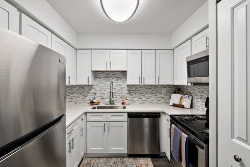 a white kitchen with stainless steel appliances and white cabinets