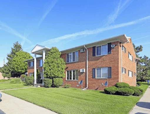 A red brick building with a white porch and a covered walkway.