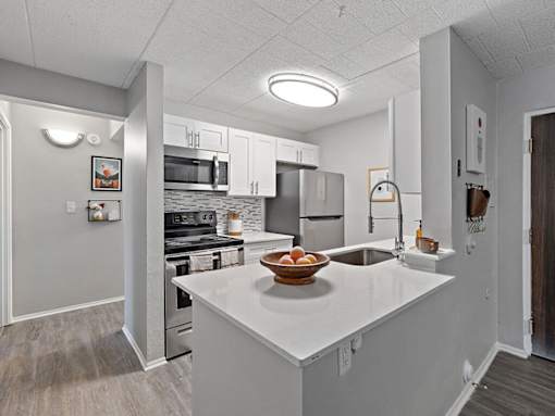 A kitchen with a white countertop and a bowl of fruit on it.