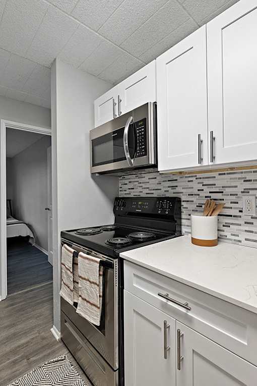 A kitchen with a black stove top oven and a black microwave above it.