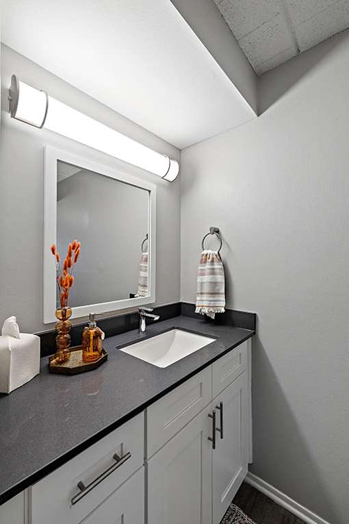 A bathroom with a sink, mirror, and towel rack.