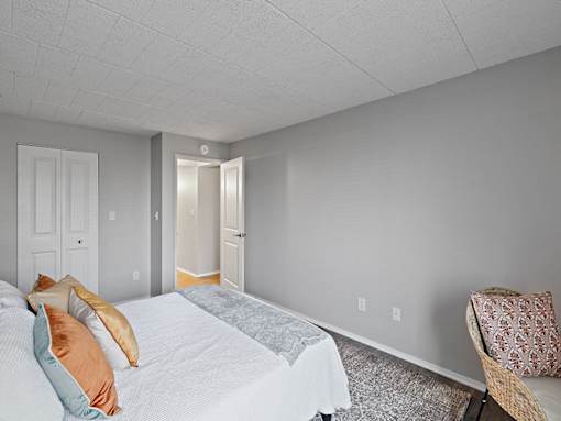 A bedroom with a bed, pillows, and a chair.