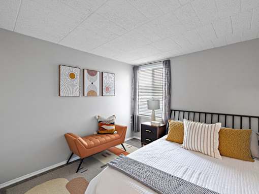 A bedroom with a bed, a chair, and a nightstand.