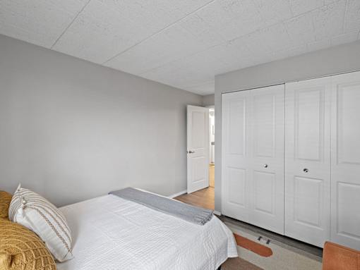 A bedroom with a bed, pillows, and a wooden floor.