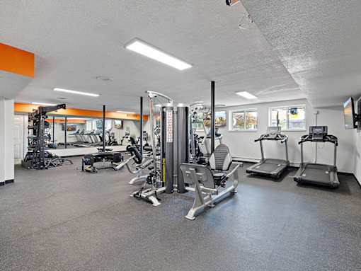A gym with a variety of equipment including treadmills, weights, and exercise machines.