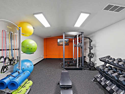 A gym with a variety of equipment including a bench, weights, and resistance bands.